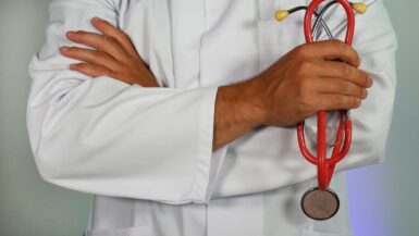 Médecin en blouse blanche tenant un stéthoscope dans les mains.