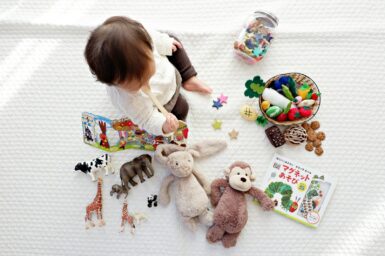 Petit garçon entouré de jouets et de doudous.